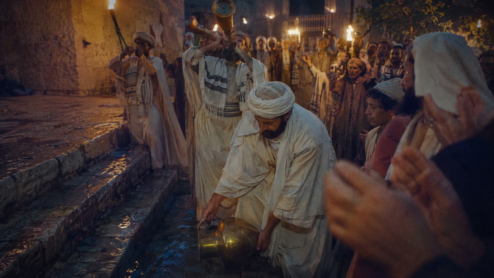 Priests pouring water from a golden pitcher during the Sukkot water ceremony, torches burning in the Temple courts